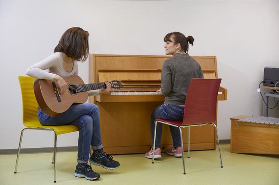 Zwei Personen musizieren, eine Frau sitzt am Klavier, eine spielt Gitarre