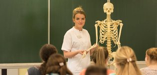 Auszubildende mit Skelett als Symbolbild für den Unterricht an der Pflegeschule Alzey