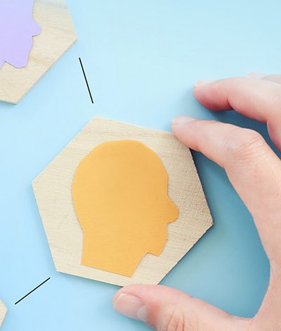 Hand puzzelt Holzteile mit Kopfsilhouetten