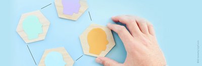 Hand puzzelt Holzteile mit Kopfsilhouetten