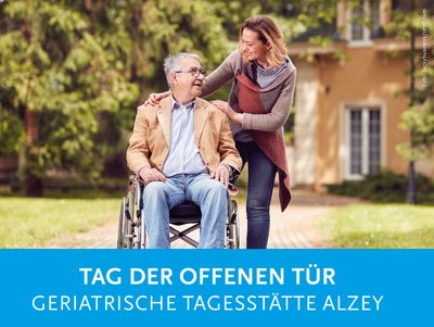 Frau geht mit einem Senioren im Rollstuhl spazieren.